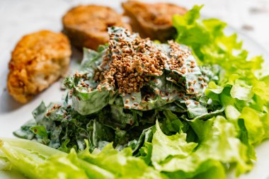 Kızarmış susam tohumu ile kaplanmış, kızartılmış kırmızı balık bifteğinin yanında ekmek kırıntıları içinde pembe somon balığı salatası ve ekşi krema salatası ile nefis bir yemek.