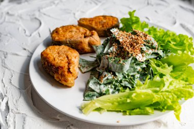 Kızarmış susam tohumu ile kaplanmış, kızartılmış kırmızı balık bifteğinin yanında ekmek kırıntıları içinde pembe somon balığı salatası ve ekşi krema salatası ile nefis bir yemek.