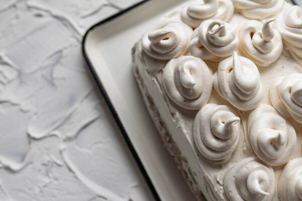 Cream dessert of airy Italian meringue. Whipped egg whites with hot sugar syrup. Light delicate cake cream in the form of a twisted peak on the top of the head in a spiral