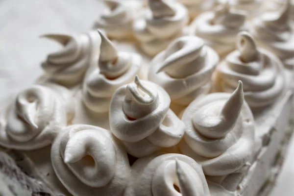 Cream dessert of airy Italian meringue. Whipped egg whites with hot sugar syrup. Light delicate cake cream in the form of a twisted peak on the top of the head in a spiral