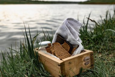 Bir dilim siyah ekmek ve yeşil çimlerin üzerinde beyaz havluyla haşlanmış tavuk yumurtası. Basit yiyeceklerle piknik yapmak. Tahta bir kutuda bitkilerle birlikte tuz ve çiçeklerin yanında..