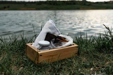 Bir dilim siyah ekmek ve yeşil çimlerin üzerinde beyaz havluyla haşlanmış tavuk yumurtası. Basit yiyeceklerle piknik yapmak. Tahta bir kutuda bitkilerle birlikte tuz ve çiçeklerin yanında..