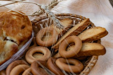 Yenebilir un kompozisyonu bir sepet içinde bir yatak örtüsü üzerinde pişirme, doğadaki altın arpa kulakları arasında. Kocaman bir çörek, vanilyalı kraker ve simit.