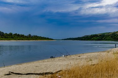 Rostov bölgesindeki tatlı su nehri Don 'u ile basit bir manzara. Sıcak mevsim, yaz, kumlu sahilde bulutlu gökyüzü ve yeşil bitki örtüsü.