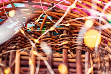 İnce bir çelenk üzerindeki küçük sarı fenerlerden oluşan bulanık bir arka plan. Hasır kahverengi ahşap sepetin içinde hafif bir ışık var. Sihirli peri masalı bayramı ya da Noel