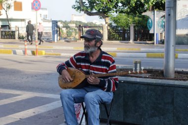 Antalya, Türkiye - 13 Mayıs: Eski bir sokak müzisyeni bir gitar benzeyen bir yerel yaylı enstrüman çalıyor. 13 Mayıs 2018, Antalya, Türkiye