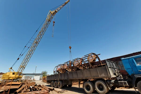 Yapıların büyük metal kamyona endüstriyel kaide üzerinde bir vinç ile yükleme
