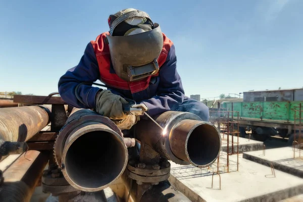 Welding works at installation of the new pipeline on oil refining installation with use of manual arc welding