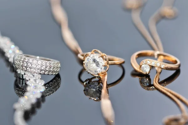Goldringe Mit Diamanten Perlen Und Edelsteinen Liegen Auf Der Reflektierenden — Stockfoto