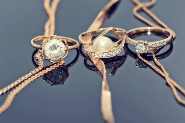 Золоті Кільця Діамантами Перлами Дорогоцінними Каменями Лежать Відбиваючій Поверхні Трьома — стокове фото