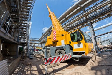 Bir büyük 100 tonluk bir kamyon vinç gelişeceğini bacakları ve genişletilmiş boom ile yeni Petrokimya Kompleksi dükkanı inşaatta standları