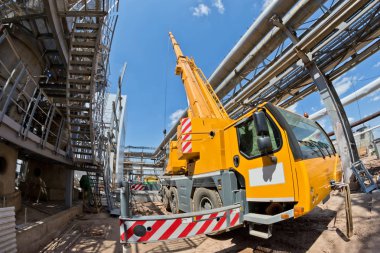 Bir büyük 100 tonluk bir kamyon vinç gelişeceğini bacakları ve genişletilmiş boom ile yeni Petrokimya Kompleksi dükkanı inşaatta standları