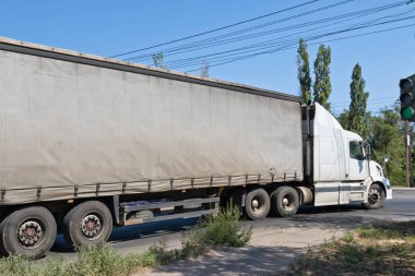 Kentin eteklerinde bir kavşakta, bir kamyon kapalı tuval konteyner ile döner