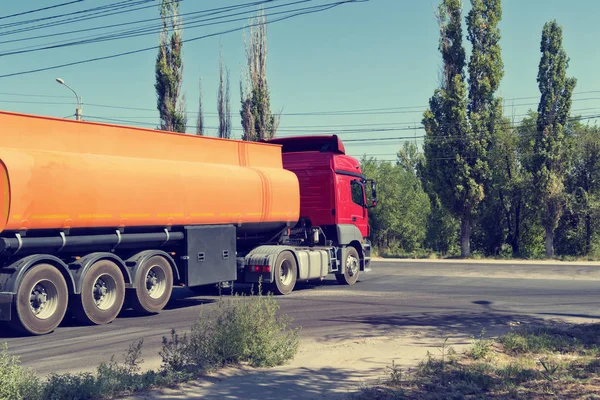 一辆卡车与一辆坦克运输石油产品在工业地区在尘土飞扬的道路上行驶 — 图库照片