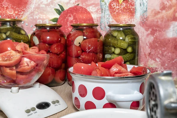 Twist tomatoes into tomato puree with an old hand grinder. Preparation of canned vegetables at home