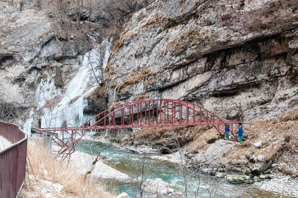Simple metal bridge over a rough mountain river in the mountainous region of the Caucasus