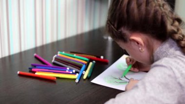 9 yaşındaki kız renkli işaretleri ile ağaçlar ve kuşlar ile resim çizer