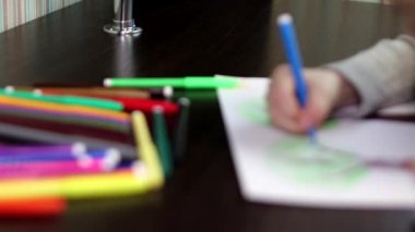 9 yaşındaki kız renkli işaretleri ile ağaçlar ve kuşlar ile resim çizer