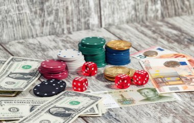 Renkli casino fişi, dolar, bitcoins ve kırmızı zar üzerinde ahşap masa lambası yalan. Zar üzerinde tüm dört altı düştü