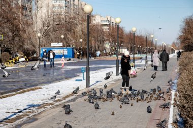 İnsanlar meydanda yürümeye beslemek güvercinler ve tohum ile serçe