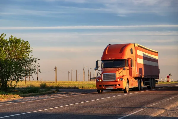 Sebuah truk merah besar mengangkut barang-barang di jalan jarak jauh — Stok Foto