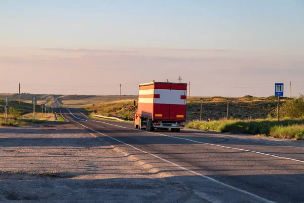 Büyük kırmızı bir kamyon uzun mesafeli bir yolda mal taşır — Stok fotoğraf