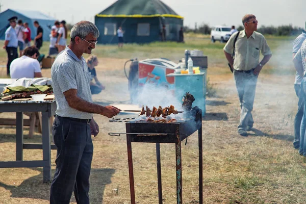 Человек жарит мясо на гриле на шампуре для традиционных блюд — стоковое фото