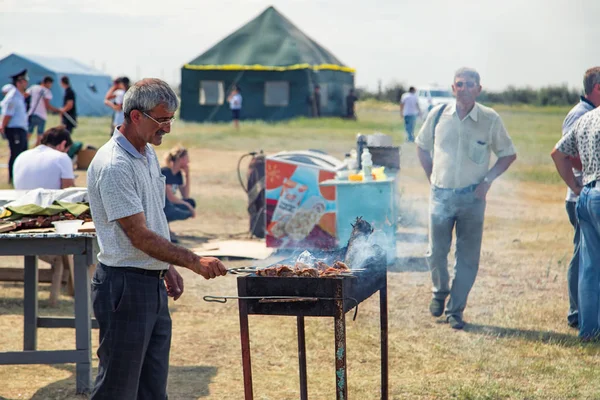 Een man braad vlees op de grill op spiesjes voor traditionele gerechten — Stockfoto