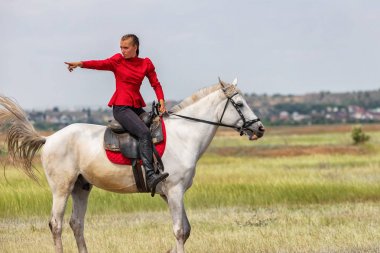 Genç kız yarıştan önce beyaz bir ata biniyor.