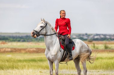 Genç kız yarıştan önce beyaz bir ata biniyor.