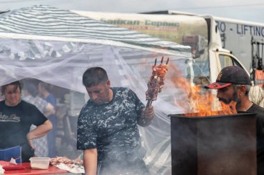 Bir adam geleneksel yemekler için şişler üzerinde ızgara et kızartma
