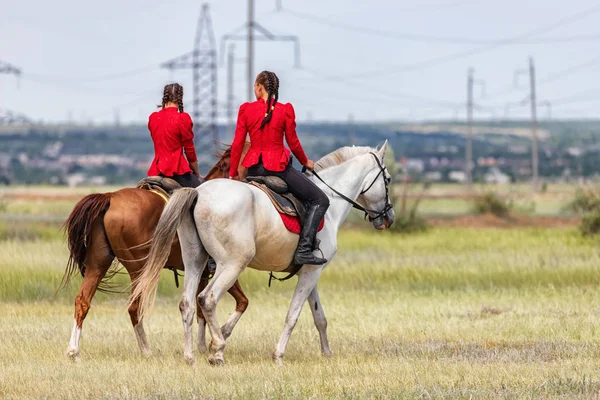 Два молодых всадника ходят вокруг своих лошадей в поле перед — стоковое фото