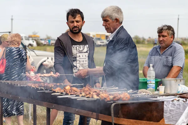 A man roasts meat on the grill on skewers for traditional dishes — Stock Photo, Image