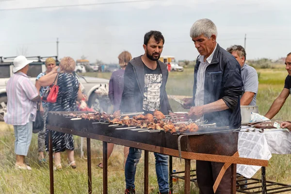 A man roasts meat on the grill on skewers for traditional dishes — Stock Photo, Image