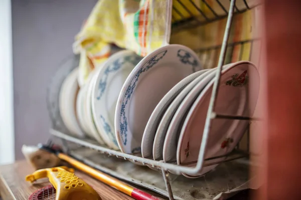 Ceramic plates are in an old dryer on a dusty cupboard — Stock Photo, Image
