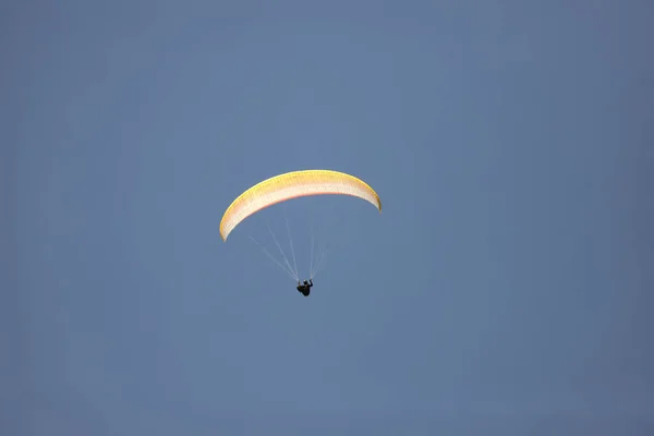 リゾートエリアで黄色のパラシュートでパラグライダーを飛ぶ観光客 — ストック写真