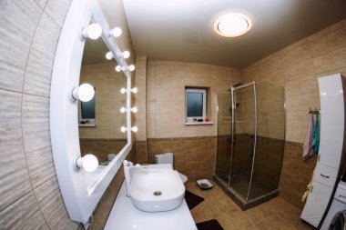 Banyonun içi büyük ışıklı bir ayna, banyo ve zarif bir lavabo ile dolu.