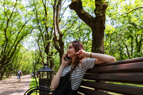 Çekici Kızıl Saçlı Kız Parkta Bir Bankta Oturuyor Cep Telefonuyla — Stok fotoğraf