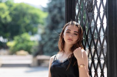 Çekici kızıl saçlı genç kız parkta kameraya poz veriyor.