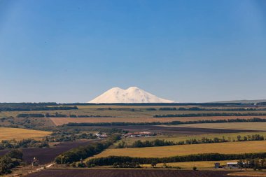 Elbrus 'un tarım arazilerindeki karla kaplı yamaçlarının manzarası