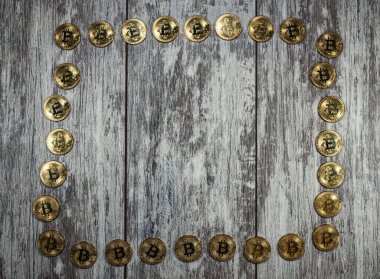 Altın bitcoin paralardan oluşan bir çerçeve ahşap bir arka planda serilmiştir. Değişim, para ve kripto para birimleri hakkında bir metin yazma gününün arkaplanı