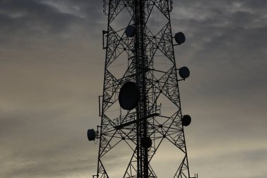 Telekomünikasyon kule anten ve uydu çanağı günbatımı gökyüzü arka plan.