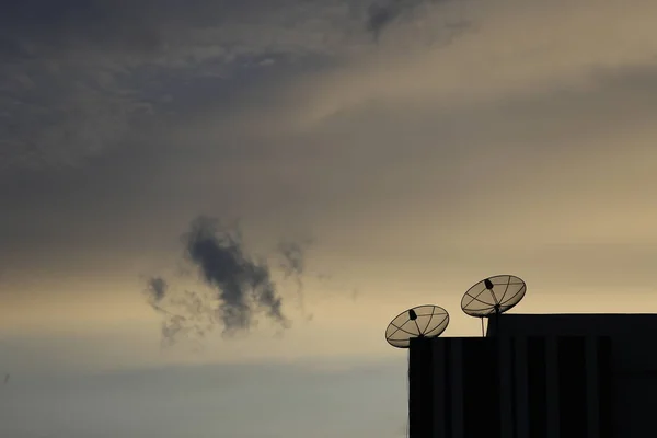 Telecommunication tower Antenna and satellite dish at sunset sky background.