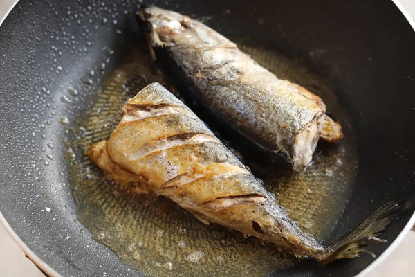 Frying fishes in frying pan.