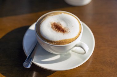 Cappuccino kahve sıcak altın sabah güneşi ile ahşap arka plan.