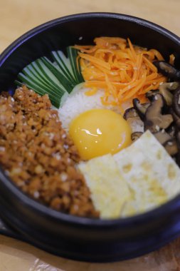 Koreli Bibimbap tabağı, ahşap arka planda pirinç ve sebze.