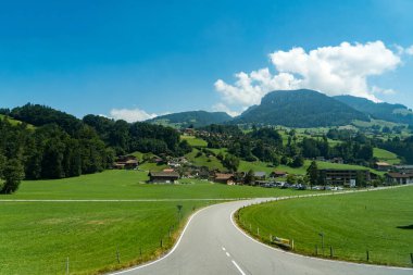 Train ride along Lake Thun with Thun city, green fields, and alpine houses on the way to Zermatt, Switzerland