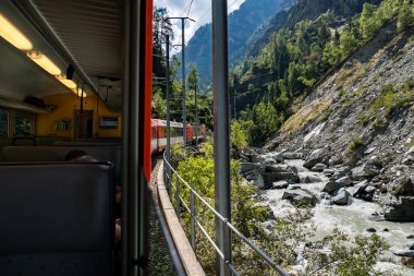 Train ride along Lake Thun with Thun city, green fields, and alpine houses on the way to Zermatt, Switzerland