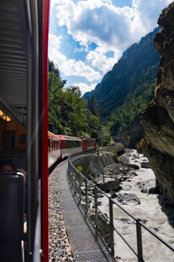 Train ride along Lake Thun with Thun city, green fields, and alpine houses on the way to Zermatt, Switzerland