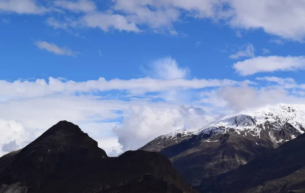 View over the hill with mountain trail and snowy mountains on the background. Beautiful mountain trail landscape.